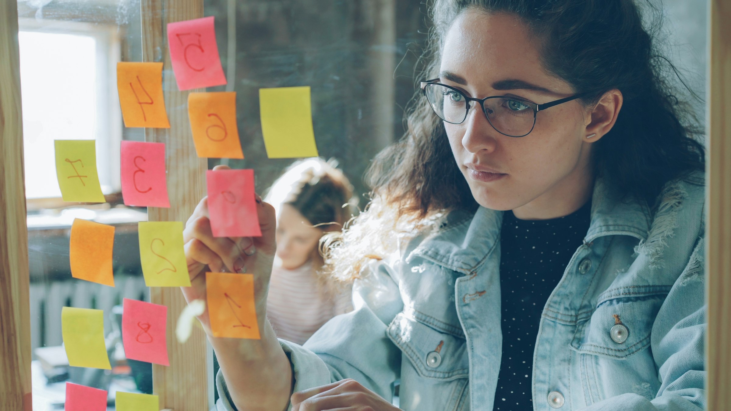 Woman organizing sticky notes on a glass wall